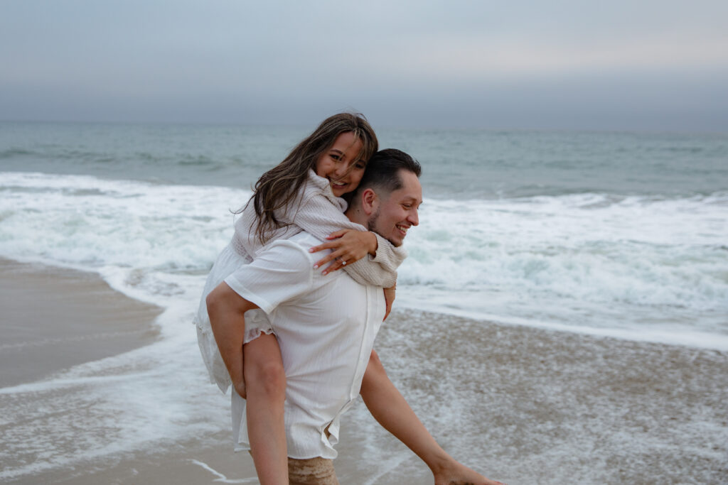 Beach engagement photo. Girl getting piggy back on beach. 